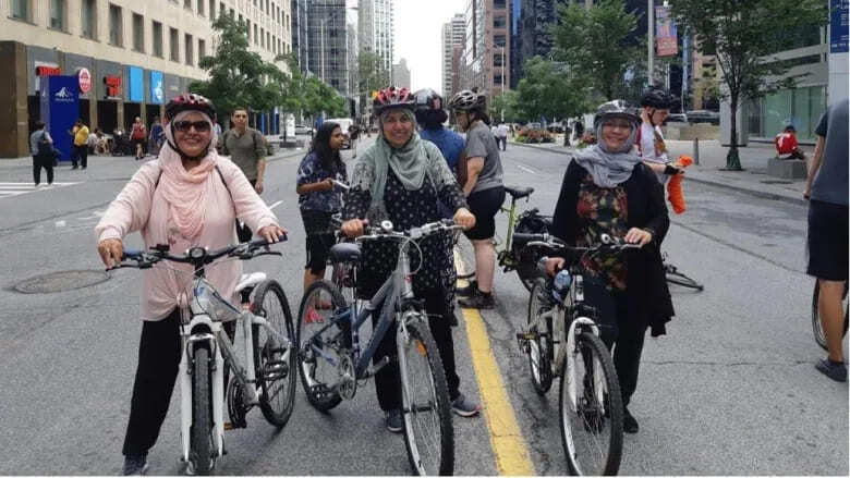 Three smiling women holding their bikes
