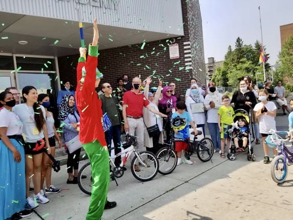 People with bikes smiling looking at a clown shooting confetti